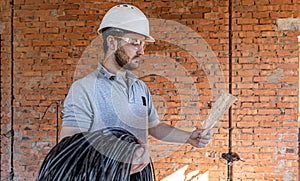 A worker at a construction site holds an electrical cable