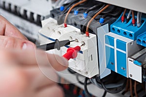 Electrician examining fusebox with multimeter probe