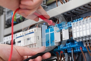 Electrician examining fusebox with multimeter probe photo