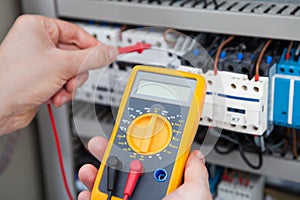 Electrician examining fusebox with resistance tester