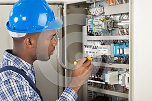 Electrician Examining Fusebox With Screwdriver