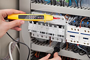 Electrician examining fusebox with voltage tester