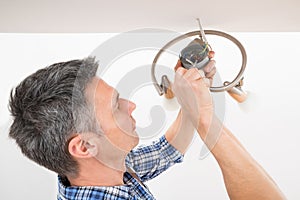 Electrician fixing light on ceiling