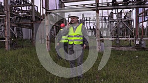 Electrician with folder using smartphone in electrical substation