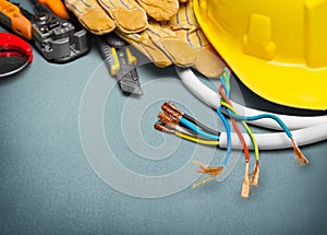 Electrician gloves and tools on wooden background