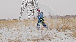 Electrician going repair the wires at power line on the field in snow