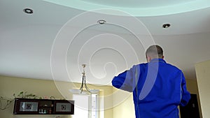 Electrician guy installing or replacing a halogen spot light lamp into ceiling