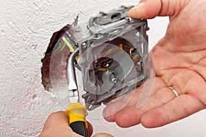 Electrician hand mounting a wall fixture