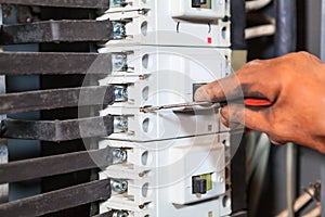 Electrician hand in rubber glove maintaining with screwdriver in high voltage box