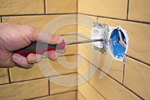 Electrician hand with screwdriver installing socket