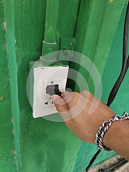 electrician hand turning off the light switch on the green wall.