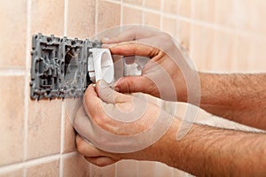 Electrician hands installing electrical wall fixture