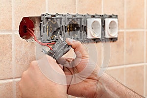 Electrician hands installing wires in electrical wall fixture