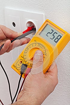 Electrician hands measuring voltage in electrical outlet