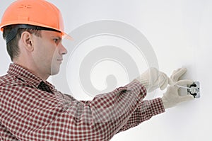 Electrician in helmet installing electrical box in appartment