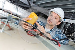 Electrician inspecting dead wires on ceiling top