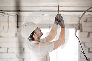 Electrician installer with a tool in his hands, working with cable on the construction site