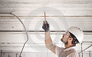 Electrician installer with a tool in his hands, working with cable on the construction site