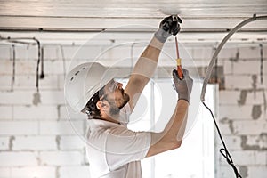 Electrician installer with a tool in his hands, working with cable on the construction site