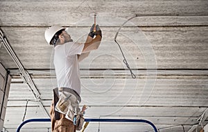 Electrician installer with a tool in his hands, working with cable on the construction site