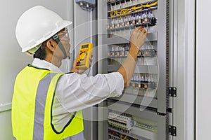 Electrician installing electric cable wires and fuse switch box. Multimeter in hands of electricians detail