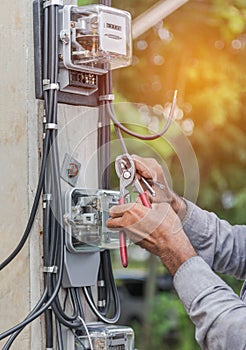Electrician installing electric meter for measuring power into electric line distribution fuseboard