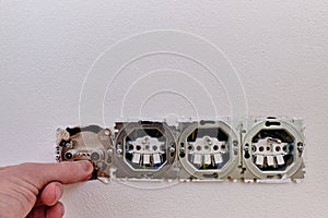 Electrician installing electric outlet socket on a white wall