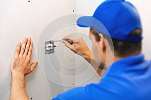 Electrician installing electrical outlet on the wall