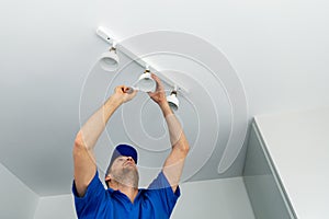 Electrician installing led light bulbs in ceiling lamp photo