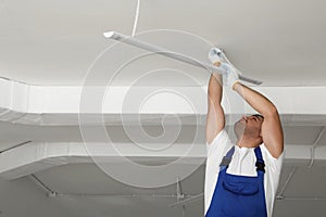 Electrician installing led linear lamp indoors, space for text. Ceiling light