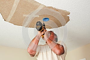 Electrician installing light fixture on ceiling photo