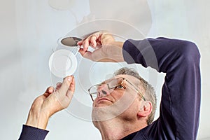 An electrician installs ceiling lighting in living room.