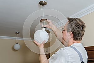 Electrician is instilling a ceiling lamp.