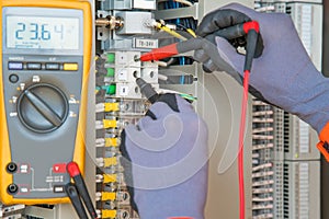 Electrician and instrument worker wearing safety gloves measuring voltage and checking electric circuit by using digital meter photo