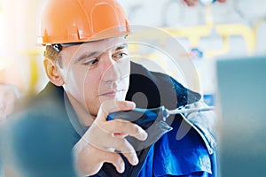 Electrician or instrumentation fitter with screwdriver adjusts operation of pressure gauge at gas industrial facility