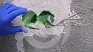 Electrician insulates wires with tape socket mounting box Wires and outlets protrude from the wall