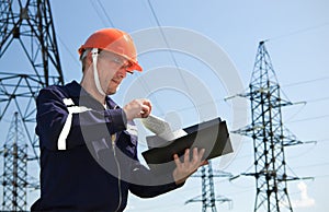 Electrician looking working drawings on the background of electric pylons