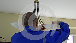 Electrician man changing light bulbs in chandelier. Back view.