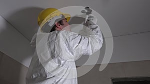 Electrician man with handsaw cutting hole in ceiling for lighting installation