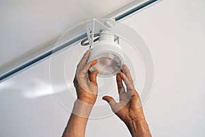 Electrician man worker installing a ceiling LED spotlight