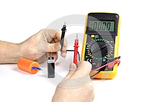 An electrician measures the capacity of a battery and capacitor with an electronic multimeter. Measuring instruments