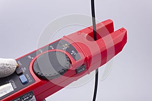 The electrician measures the current in the phase wire with a meter