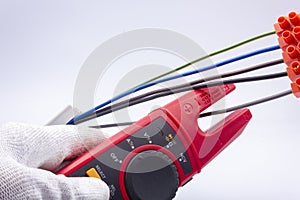 The electrician measures the current in the phase wire with a meter