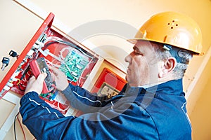 Electrician measuring electric circuit with multimeter in fuse box