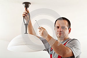 Electrician mounting ceiling lamp