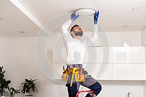 Electrician mounting ceiling lamp - installing the wires.