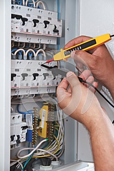 Electrician with multimeter probe at an electrical switchgear ca