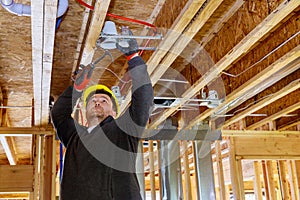 The electrician nailing to the ceiling lamp, installs the lighting lamp