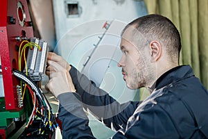 Electrician on overalls is working with energy panel and machinery equipment on plant