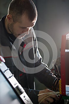 Electrician on overalls is working with energy panel and machinery equipment on plant